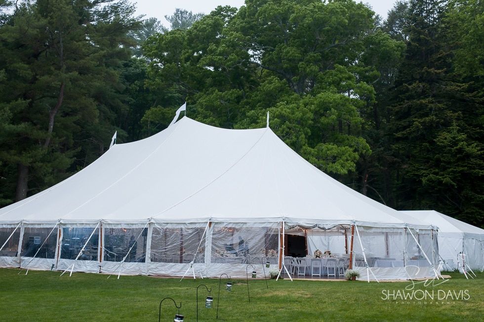 Large white event tent on a grassy field with trees in the background