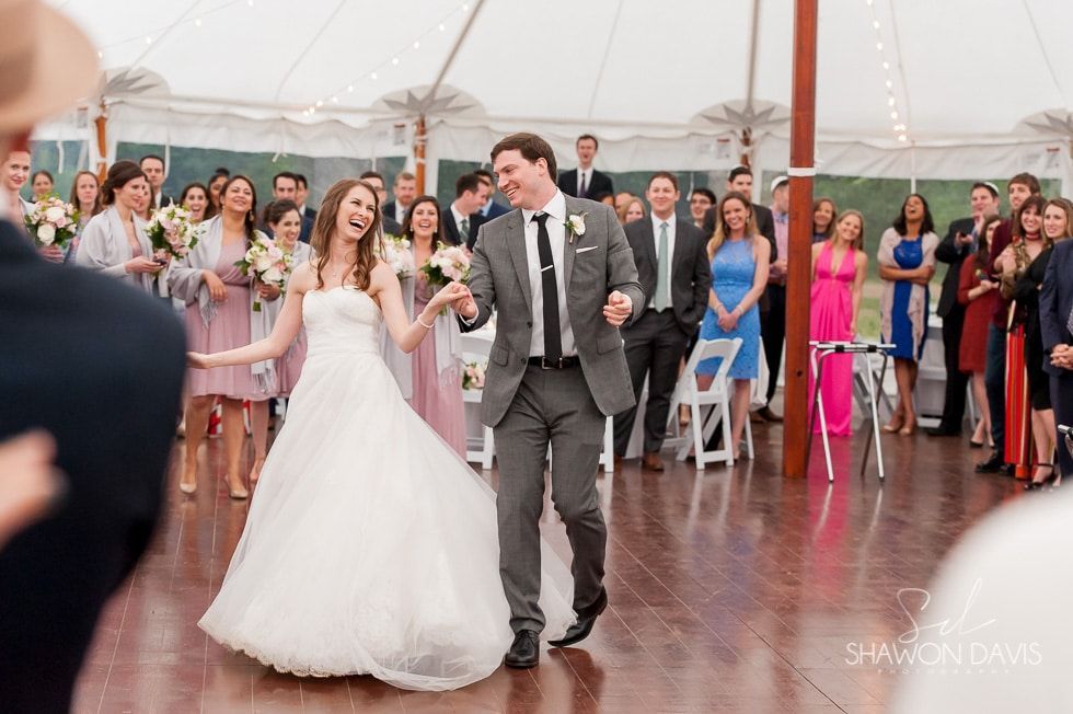 Bride and groom dancing at a wedding reception surrounded by cheering guests