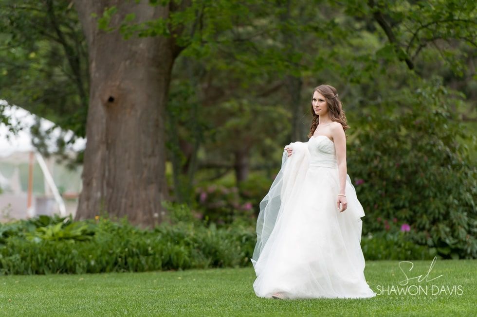 Bride in a white gown walking through a green garden.