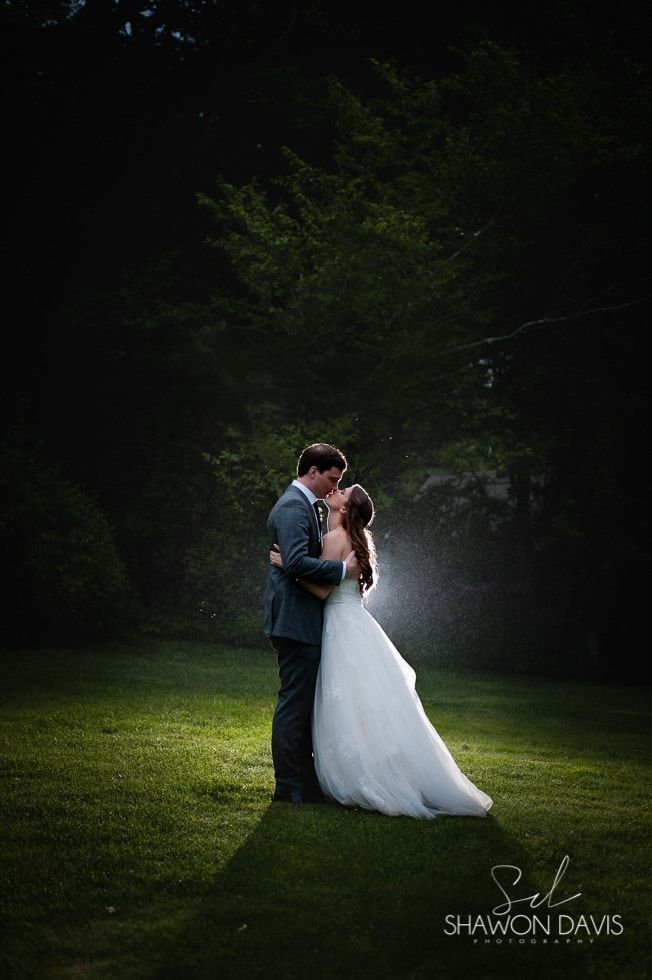 Couple embracing in a dark forest clearing, the bride in a white dress and groom in a dark suit.