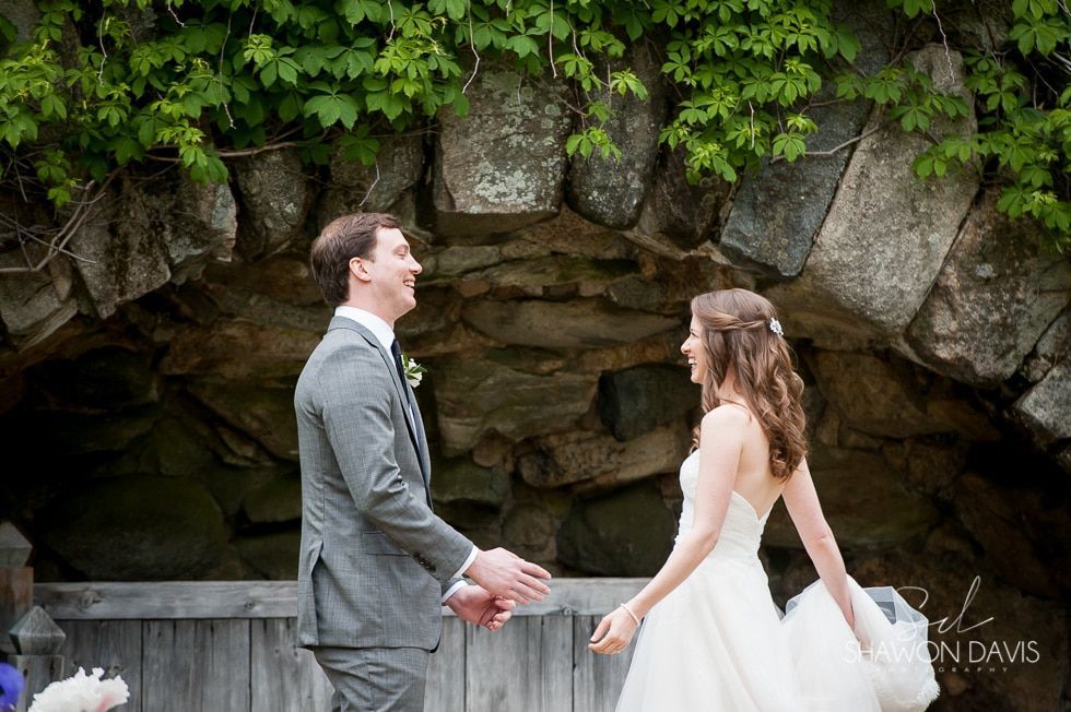 Bride and groom holding hands in front of a stone grotto
