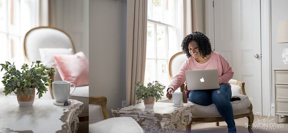 Woman using a laptop on a sofa in a bright living room with plants and a pink pillow