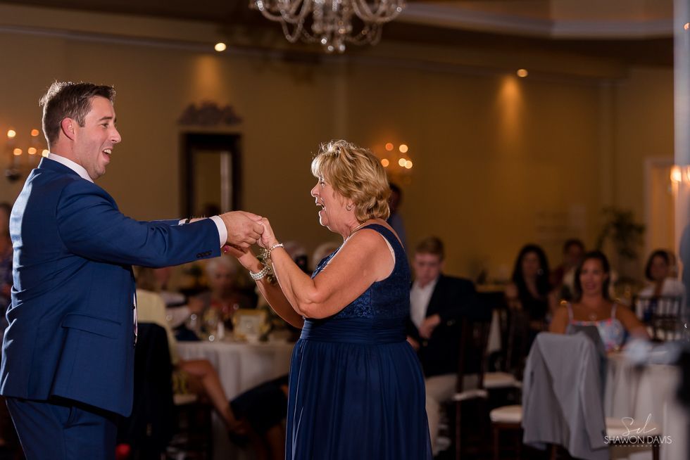 Couple dancing at a formal reception, man in blue suit and woman in navy dress smiling