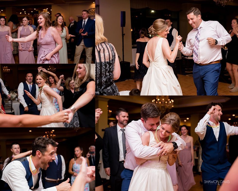 Wedding guests dancing and laughing at a lively reception with the bride and groom in formal attire