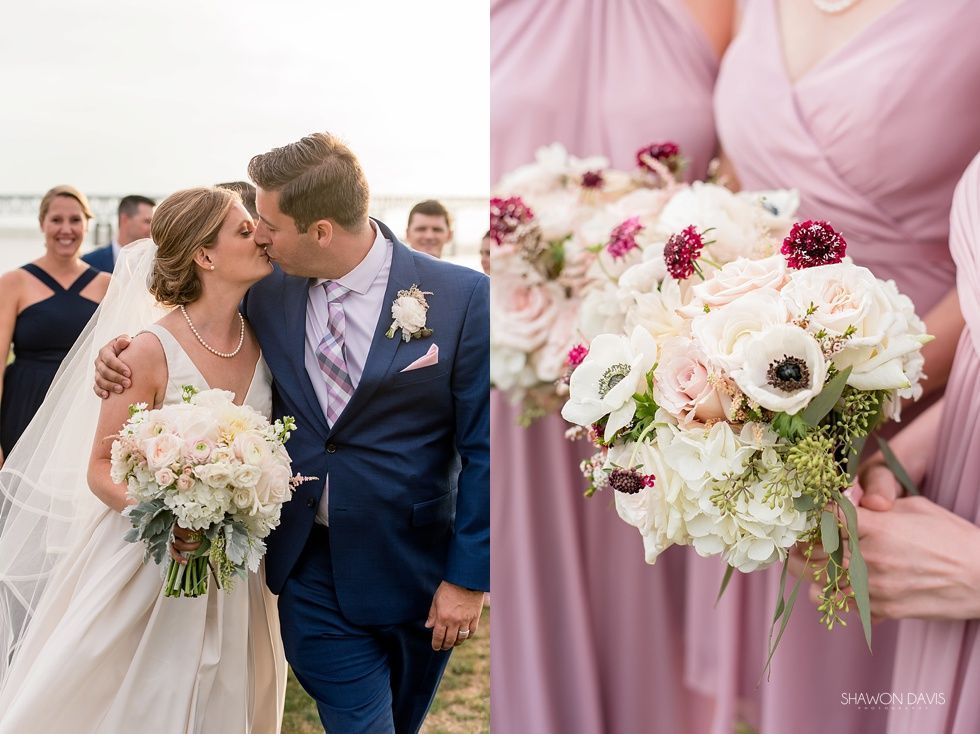 Newlyweds kiss on a beach walk while bridesmaids hold pink and white bouquets nearby