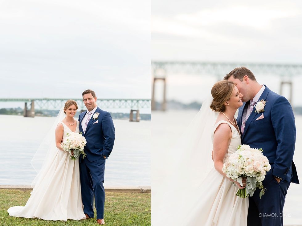 Bride and groom posing by a waterfront bridge, the couple kissing in the foreground and standing together at sunset.