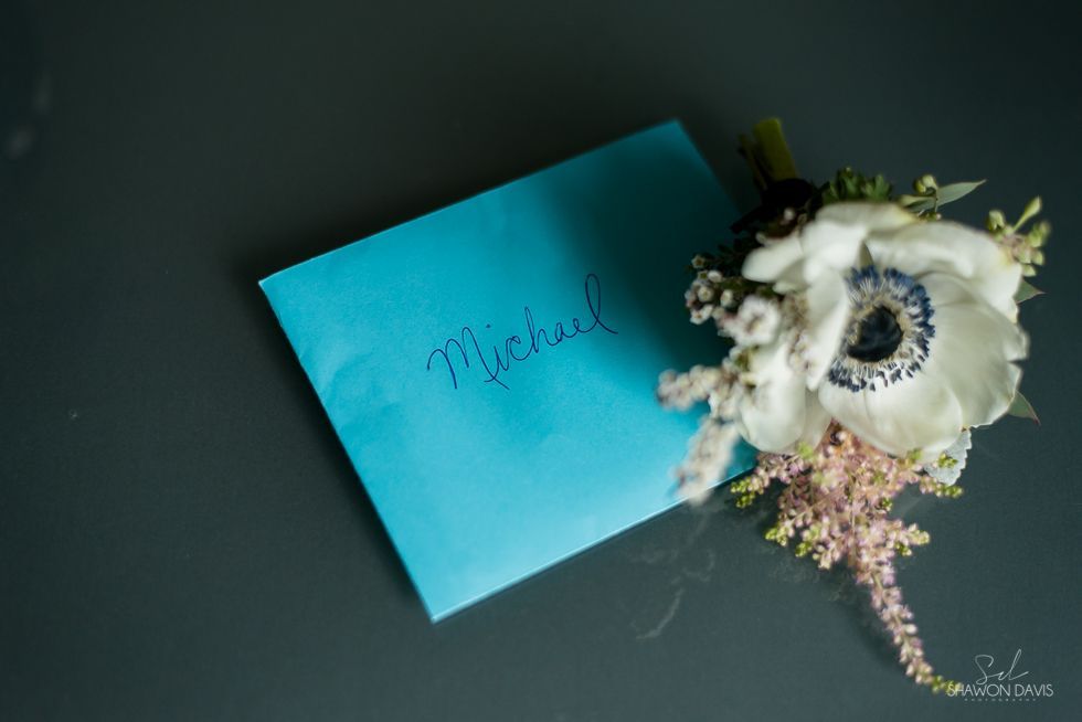 Turquoise card with white flowers on a dark background, bearing the name “Michael”