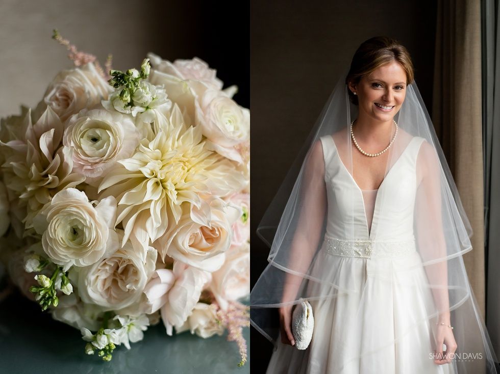 Wedding bouquet beside a bride in a white dress and veil, holding a clutch and smiling indoors