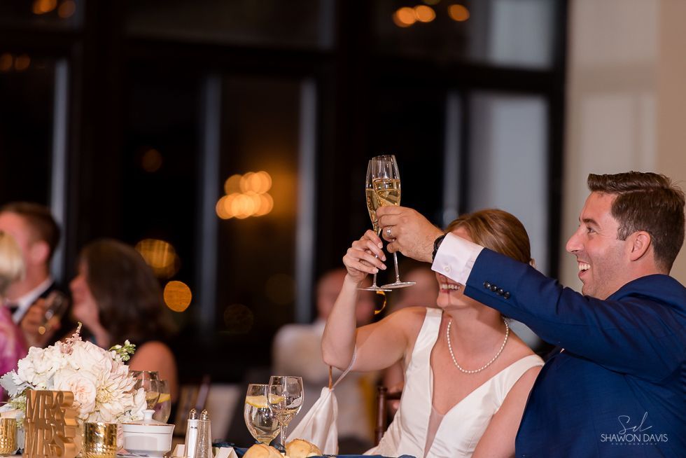 Guests toast with champagne at a warmly lit indoor wedding reception.