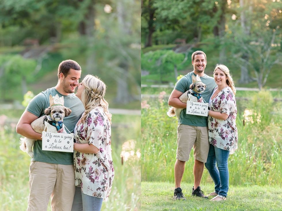 Couple holding a dog in a basket outdoors in a grassy field, smiling at each other