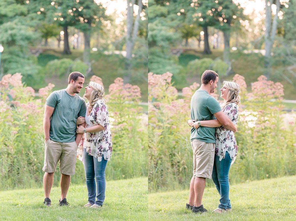 Two couples stand in a grassy park, hugging and smiling among pink wildflowers.
