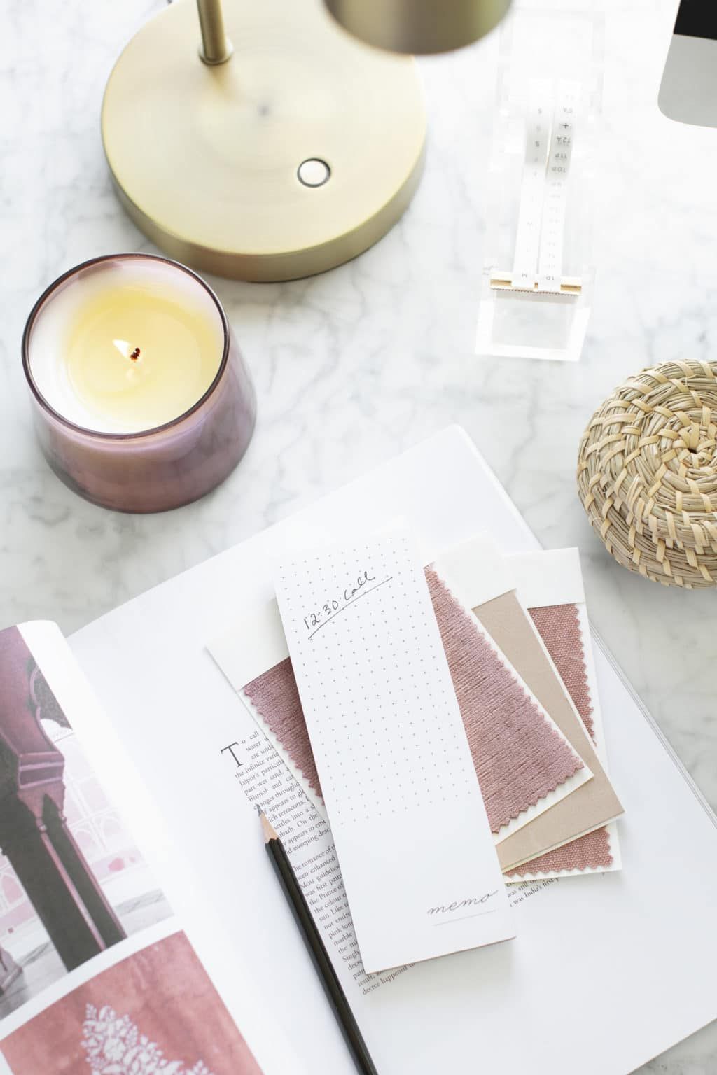 Flat lay of candles, fabric swatches, and design samples on a marble surface