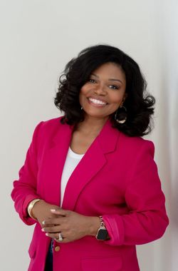 Woman smiling in a bright pink blazer against a light background