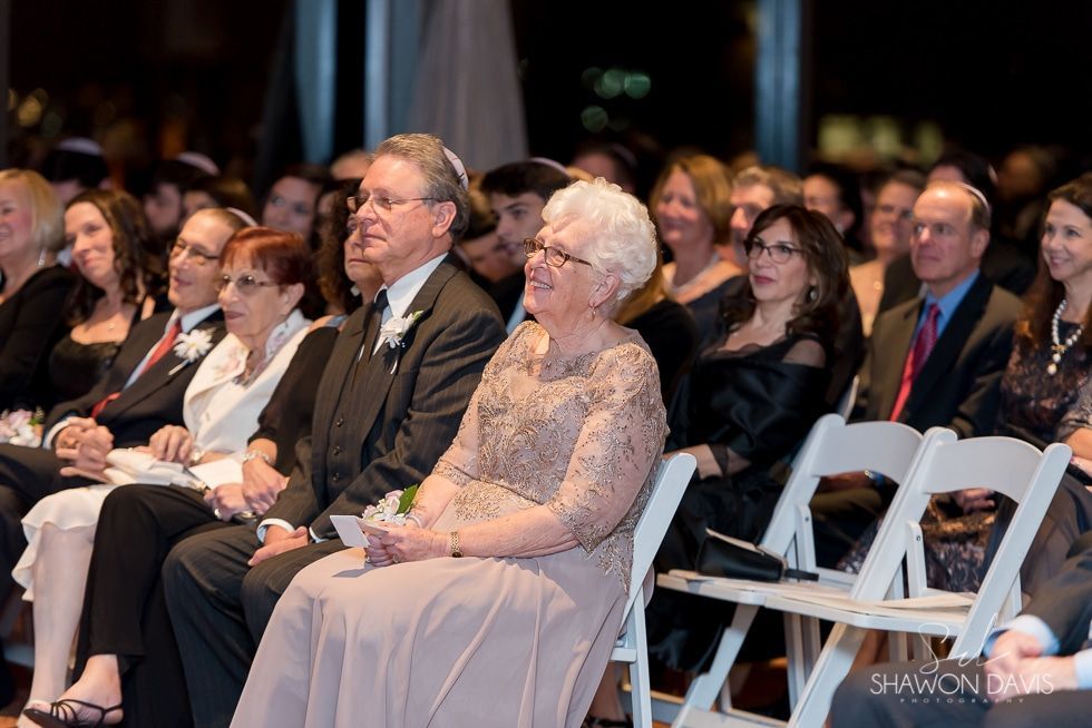 Audience seated at an indoor event, watching a presentation on stage