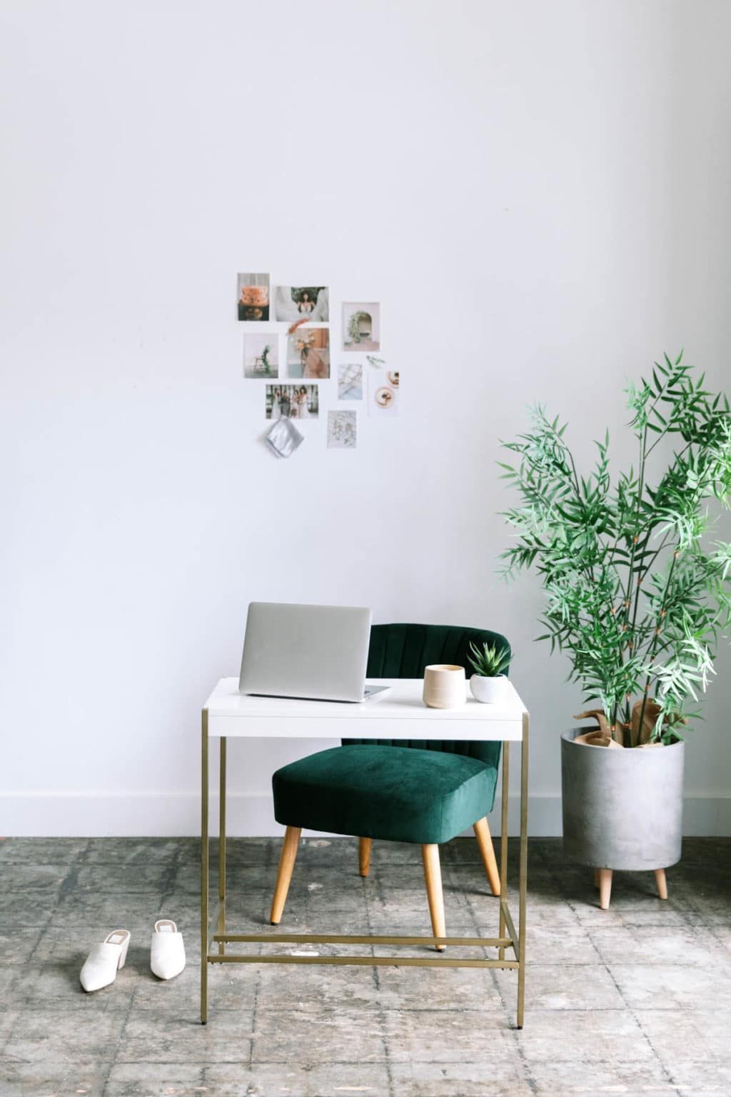 Minimal desk with laptop and chair beside a potted plant in a bright room
