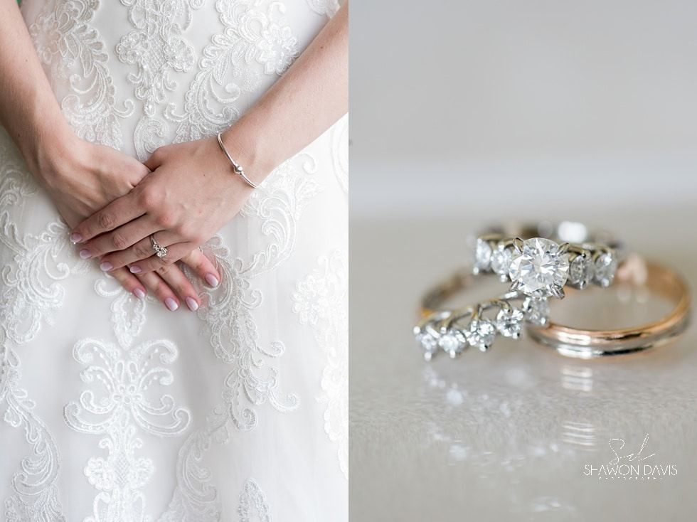 Bride’s lace dress and clasped hands beside a diamond ring on a reflective surface