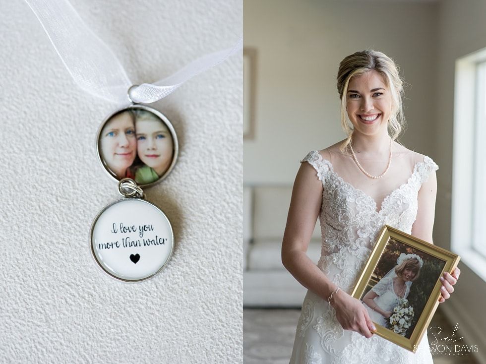 Bride holding a framed wedding photo beside a memorial keepsake on a white wall
