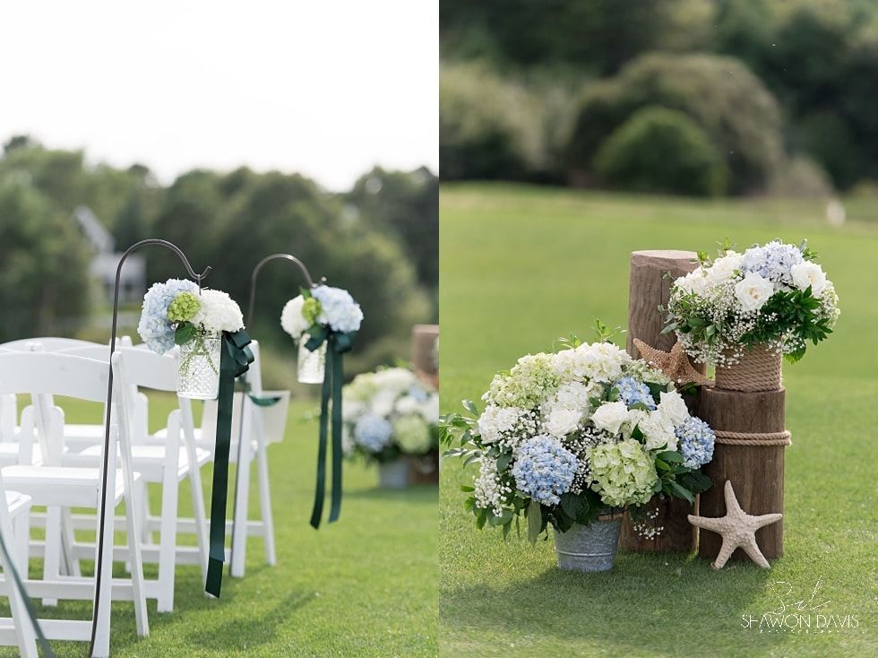 White garden chairs and floral arrangements in a grassy outdoor wedding setup.