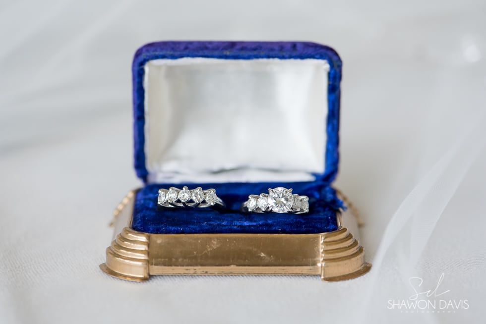 Blue velvet ring box open with two diamond rings on white background
