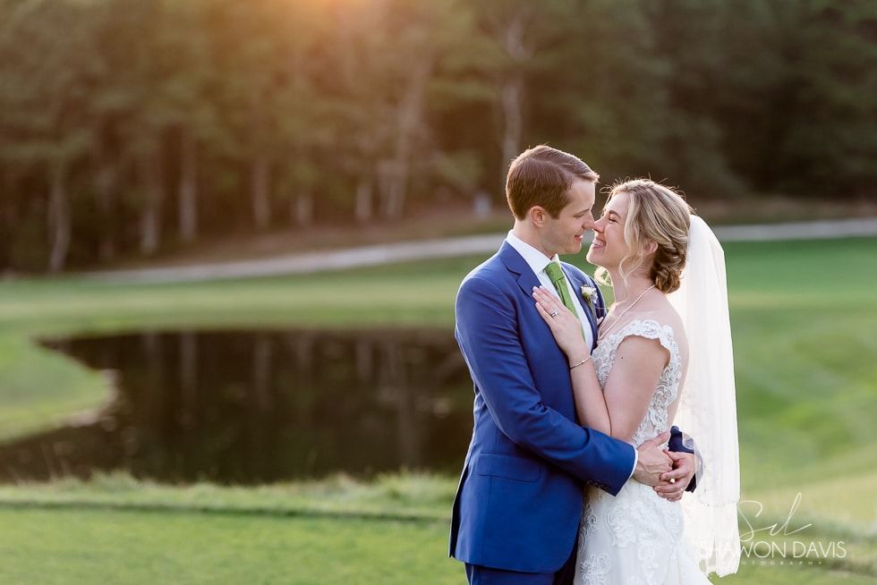 Wedding couple embracing by a pond at sunset