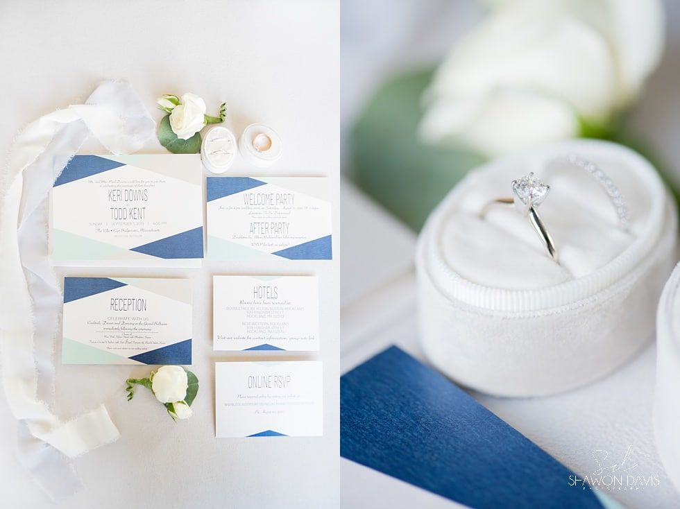 Wedding invitation suite with blue accents, white roses, and rings on a white cushion