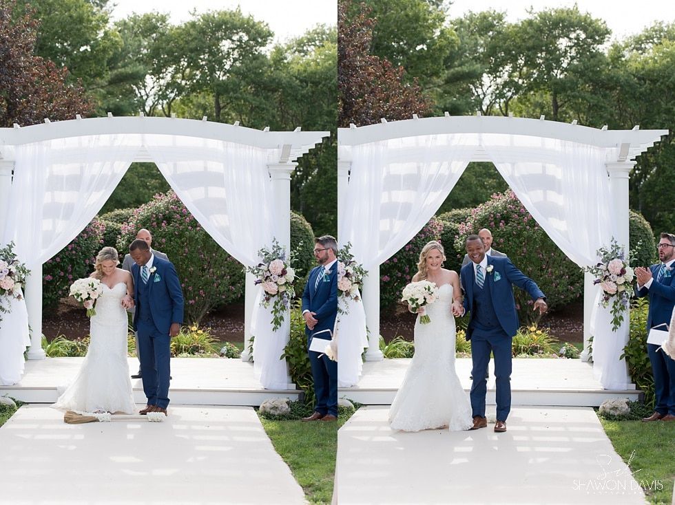 Bride and groom posing under white draped arches with floral arrangements outdoors