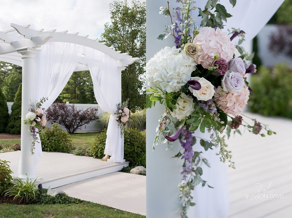 White wedding arch with sheer drapes and pastel floral arrangement in a garden setting