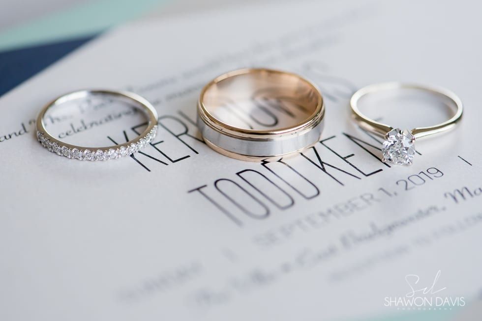 Three wedding rings on a wedding invitation with the word “TOOK” visible underneath.