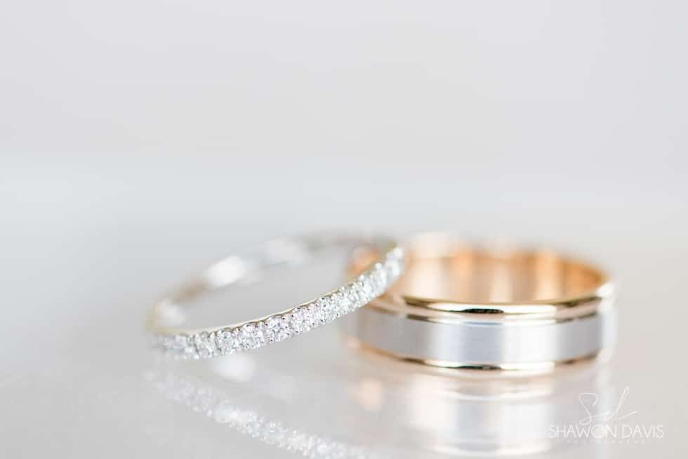 Silver and gold wedding rings on a white reflective surface