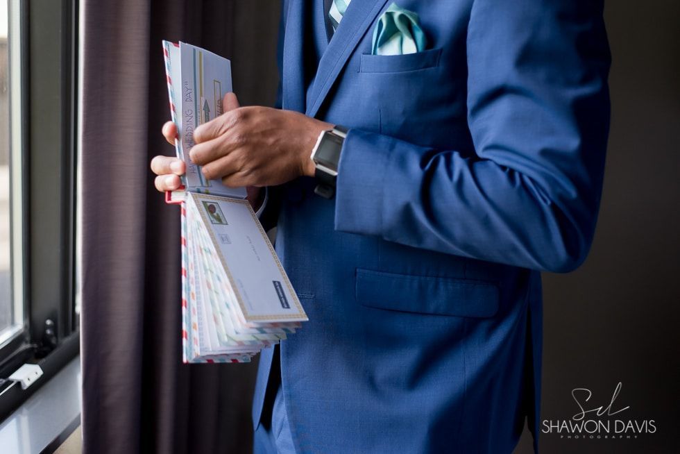 Person in a blue suit holding folders by a window.