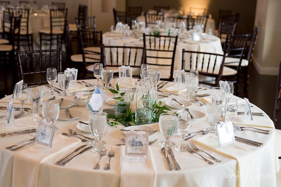 Round banquet tables set with white tablecloths, glassware, and napkins in an elegant dining hall