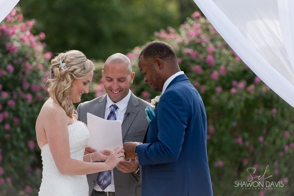 Bride and groom reading vows with officiant at an outdoor wedding ceremony