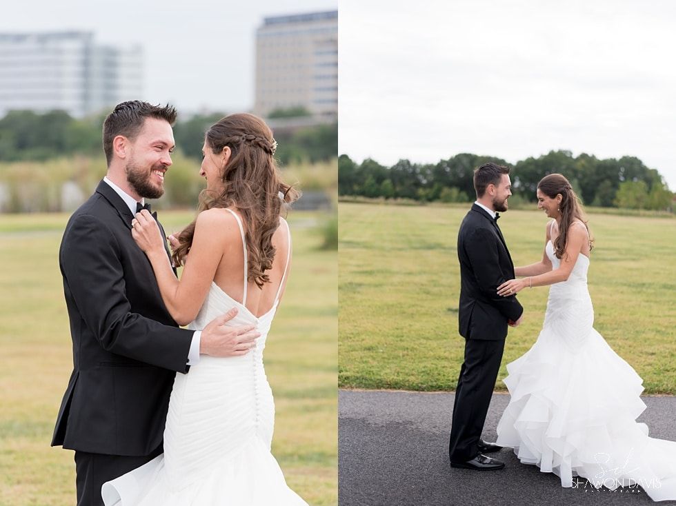 Bride and groom holding hands and smiling on a grassy field in wedding attire