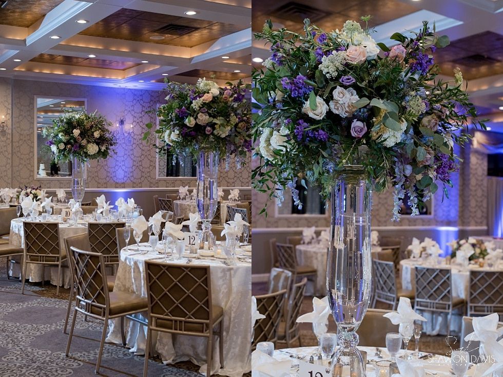 Elegant wedding reception hall with gold chairs, white tables, and tall purple floral centerpieces
