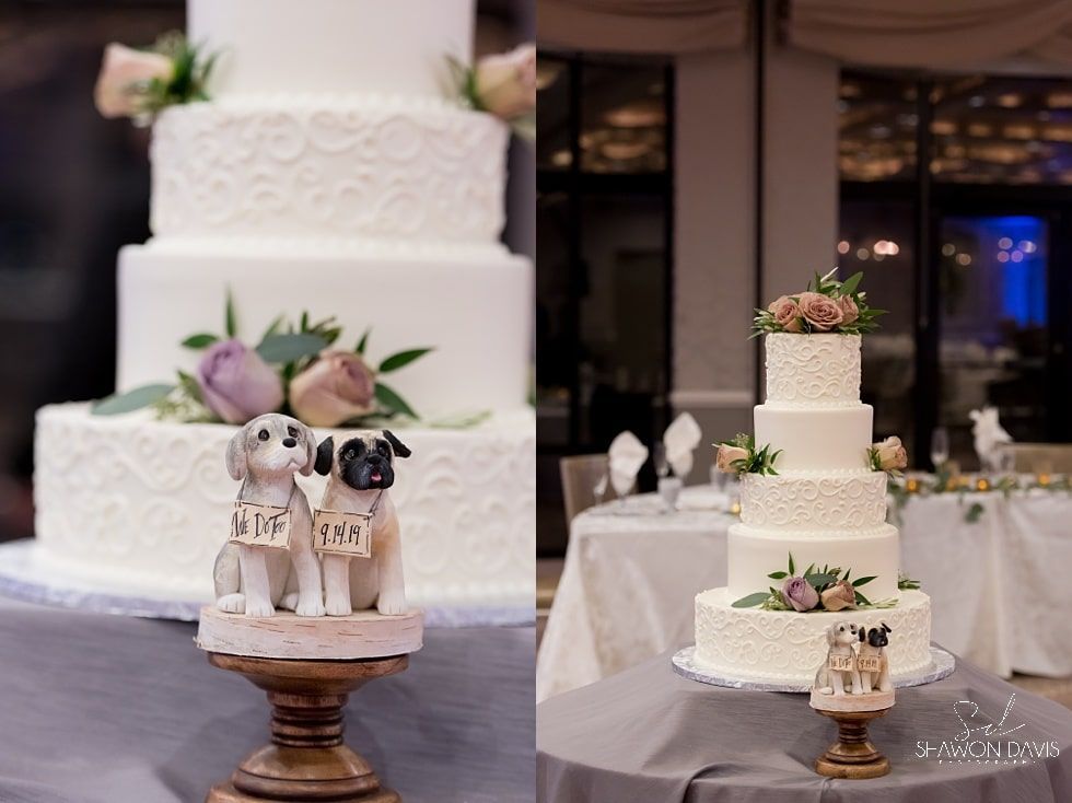 Wedding cake display with white tiered cakes and a small dog figurine topper on a pedestal table