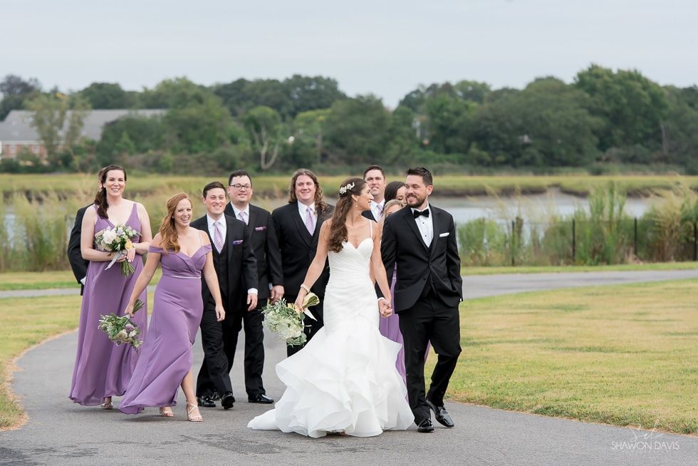 Wedding party walking together outdoors on a grassy path by a pond