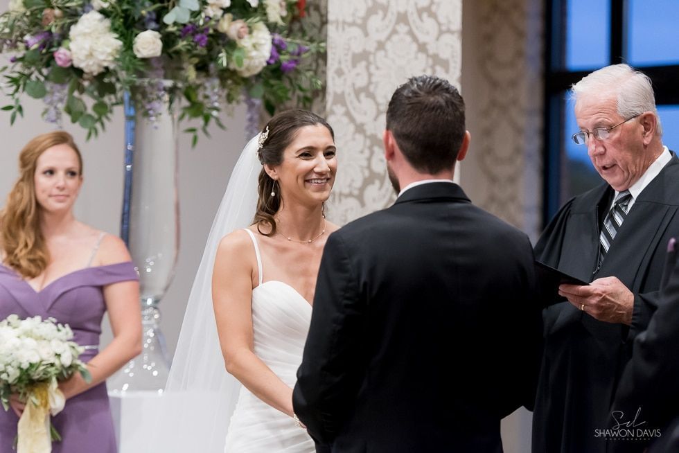 Bride and groom at the altar during a wedding ceremony, with bridesmaid and officiant nearby