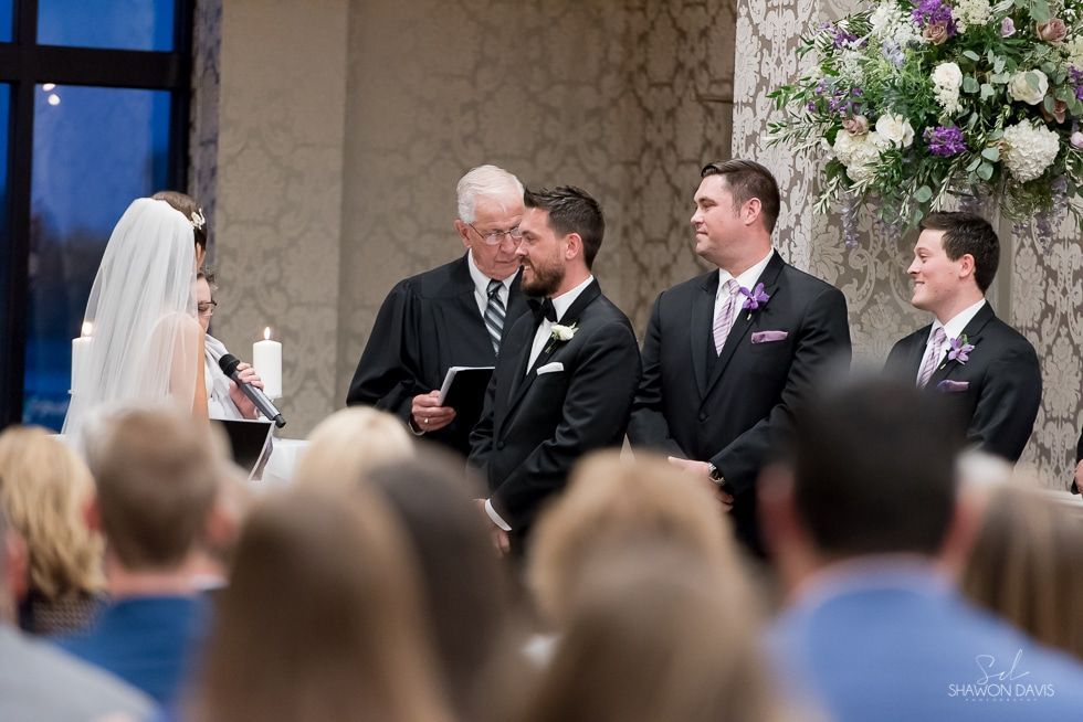 Wedding ceremony with bride, groom, officiant, and groomsmen standing at the altar.