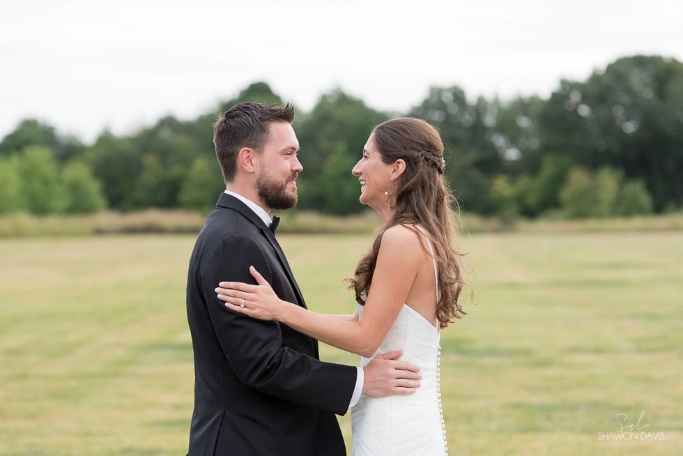 Bride and groom embracing in a grassy field outdoors