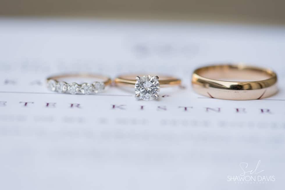 Three gold and diamond rings on a blurred white background with printed text