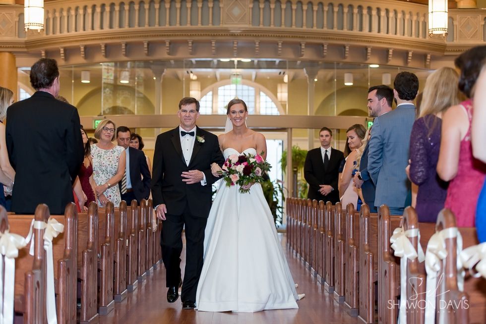 Bride and groom walking down church aisle with guests watching