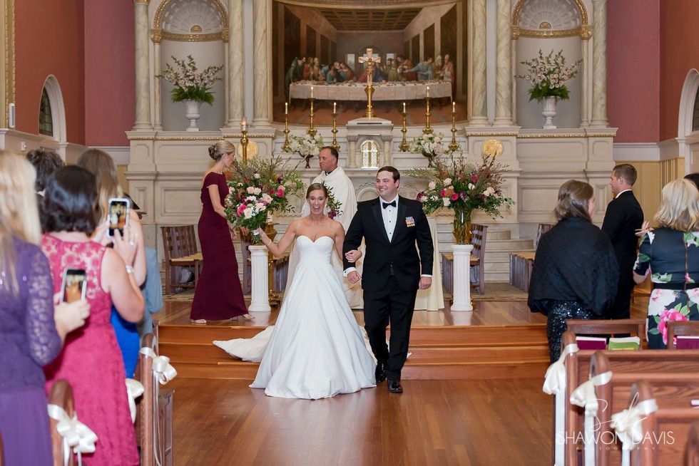 Bride and groom walking down church aisle after wedding ceremony with guests seated on both sides