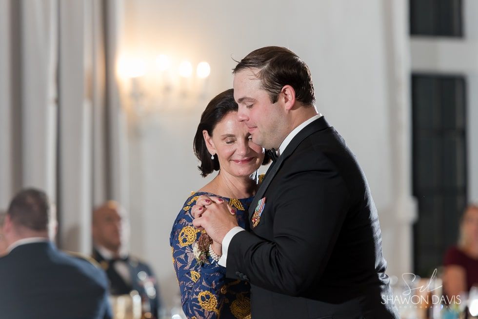 Couple slow dancing at an elegant indoor event, holding each other closely with soft smiles