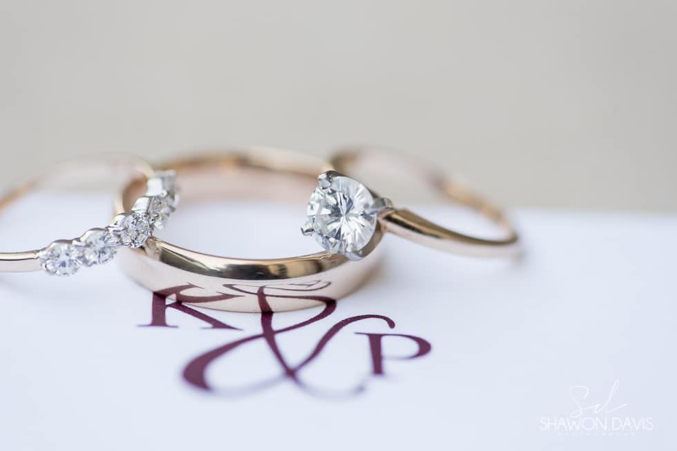 Three diamond rings on a monogrammed wedding card with a soft gray background