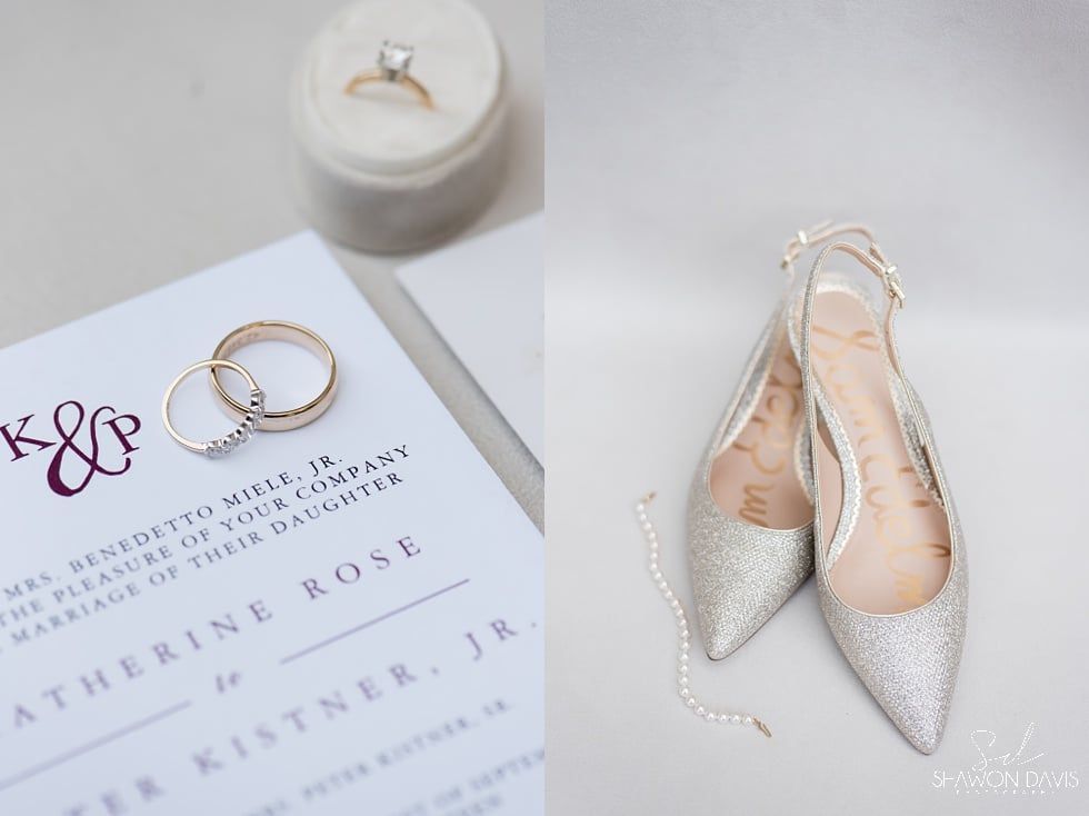 Wedding invitation, gold rings, silver pointed heels, and a small candle on a white background