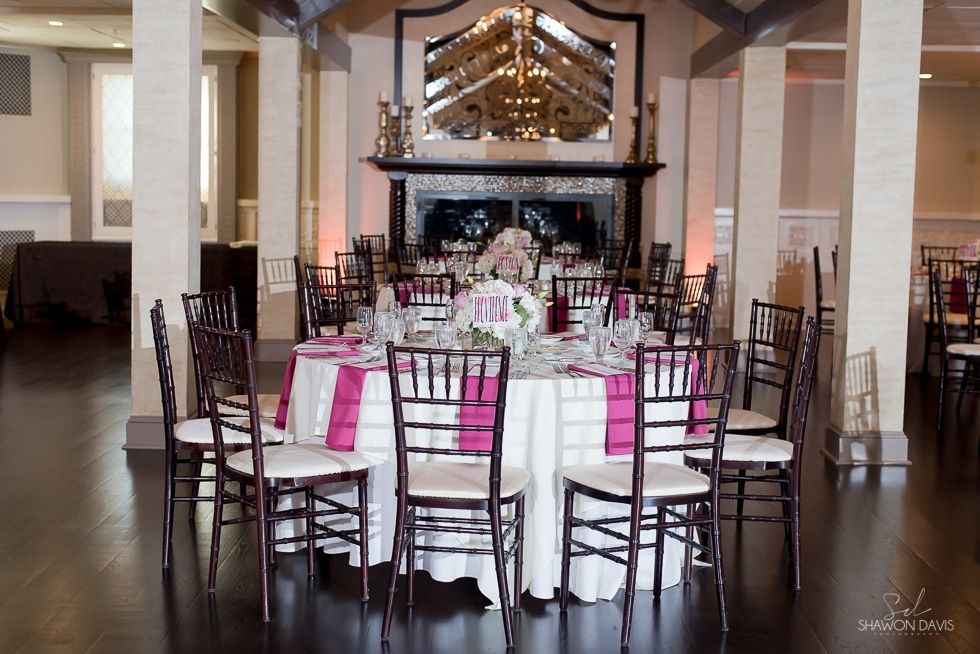 Decorated banquet table with white chairs and pink accents in a formal dining hall