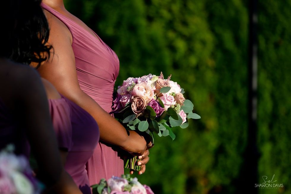 Bridesmaid in a pink dress holding a bouquet of pink flowers in a garden.