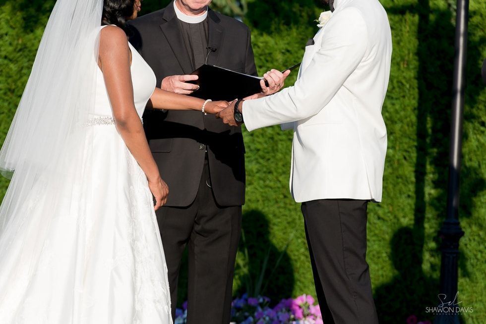 Bride and groom exchanging vows at an outdoor wedding ceremony with an officiant