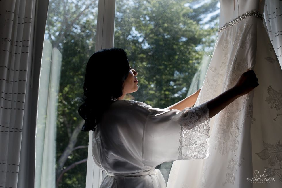 Silhouetted person opening white curtains beside a bright window with trees outside