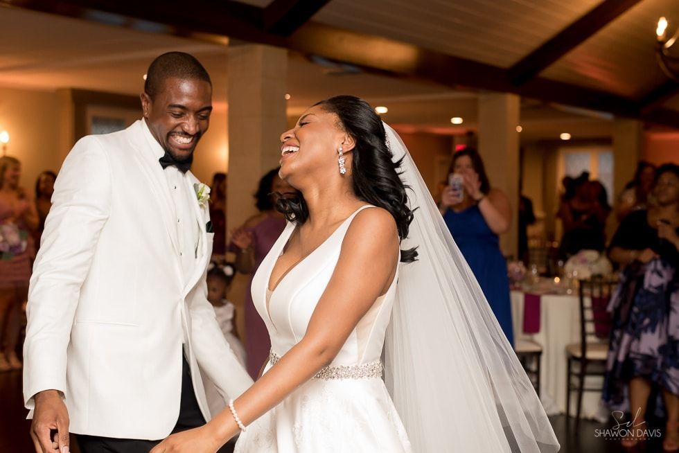 Bride and groom smiling and holding hands during a wedding reception